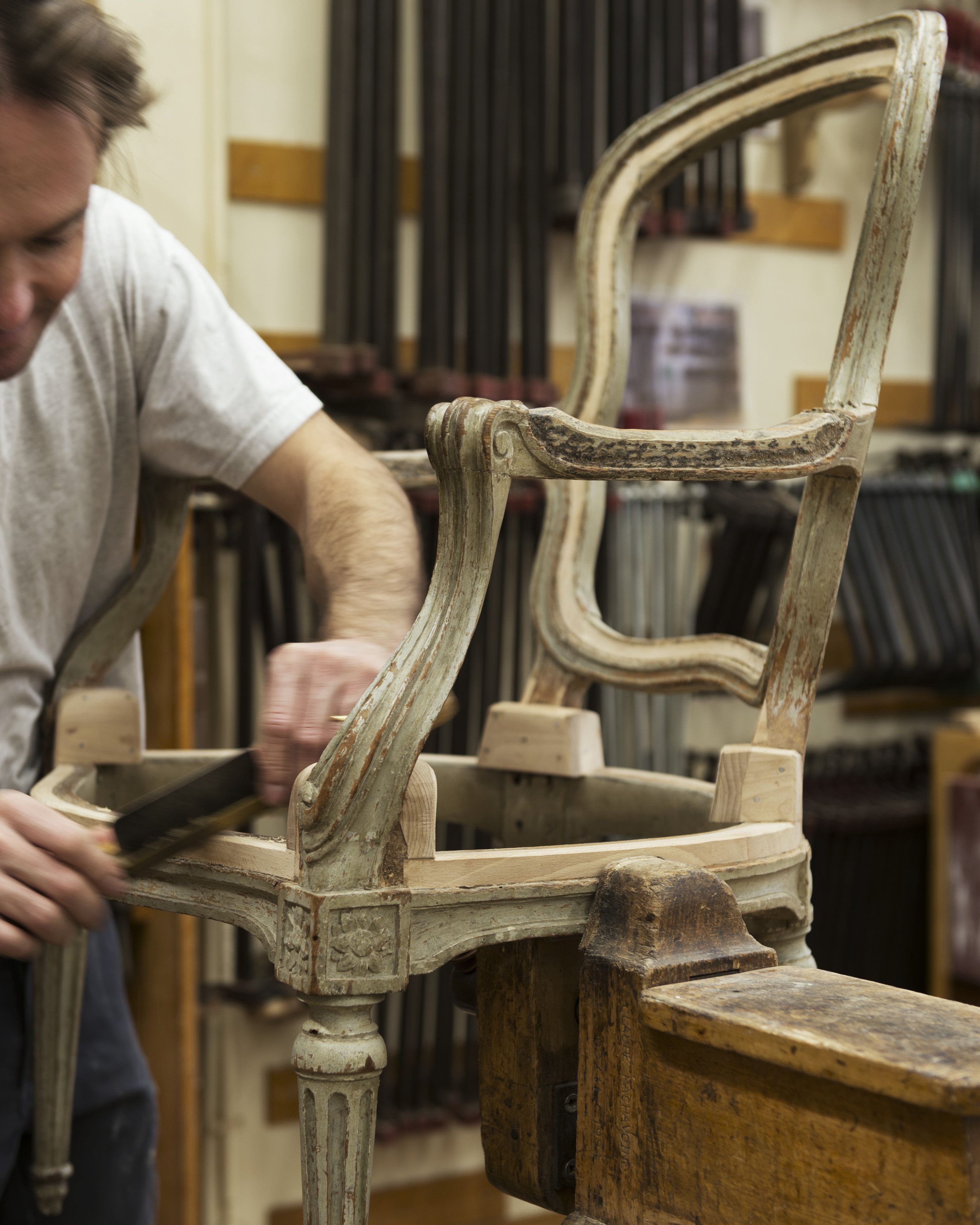 Réalisation de chanfreins sur le bâti d'un fauteuil d'époque Transition, à l'aide d'une raclatte, à l'atelier de menuiserie en sièges. La garniture sera fixée sur les chanfreins